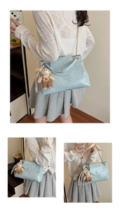 Détail d'un sac à main bleu clair texturé avec une petite breloque ours en peluche