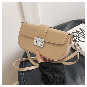 Detailed view of khaki baguette bag featuring silver geometric clasp and chain strap