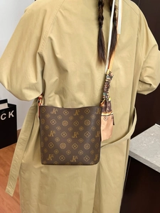 Sac seau monogramme marron classique avec détail de foulard en soie porté avec un trench-coat