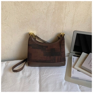 Detail shot of a vintage hobo bag with gold chain buckle and brown geometric patterns
