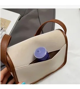Détail du sac en cuir beige et marron montrant la poche frontale fonctionnelle