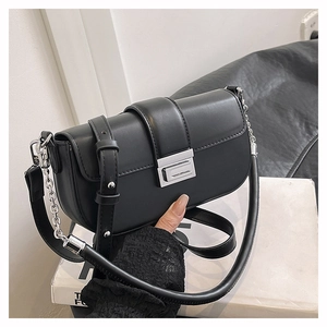 Detail showing the matte black faux leather finish and silver metal buckle of the shoulder bag