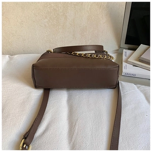Detailed base structure of a dark brown faux leather bag with fine stitching and gold chain
