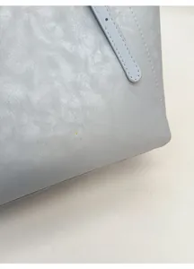 Detail of light blue leather tote bag showing fine texture and gold embossed fashion logo