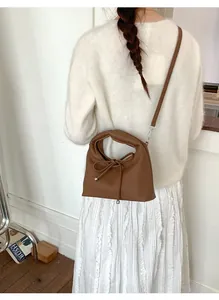 Detail of a brown pebble leather shoulder bag with drawstring bow and silver beads