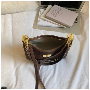 Detail shot of a dark brown leather baguette bag with a gold square lock and chain strap