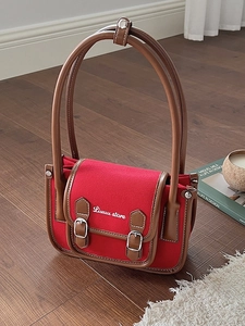 Red canvas square shoulder bag with brown leather trim and white text embroidery