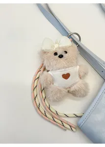 Close-up of cute plush bear bag charm with heart vest and braided lanyard detail