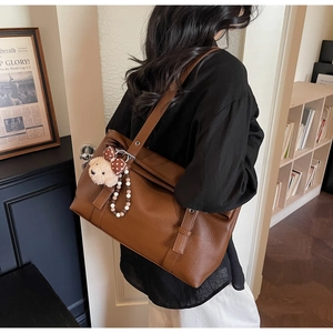 Détail du sac à bandoulière en cuir marron avec breloque ours et boucle métallique