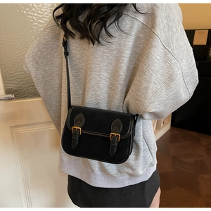 Détail du sac bandoulière noir rétro avec boucles dorées sur rabat en cuir mat