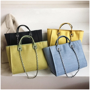 Detalle de bolsos tote de gran capacidad en varios colores con correas de cadena