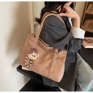 Détail du sac cabas marron en cuir grainé avec un porte-clés ours et boucle décorative