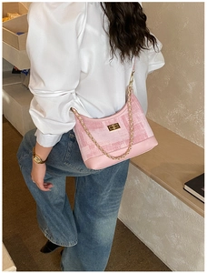 Detail of pink tweed shoulder bag with golden chain strap on model's shoulder