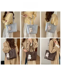 Detail view of large tote bags in blue and brown with plush bear charm and brand texture