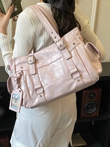 Pink faux leather large tote bag with silver buckles and a cute charm on a model
