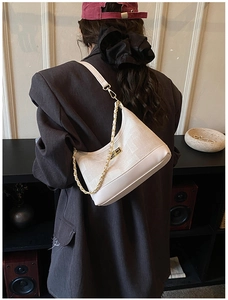 Detail of cream white shoulder bag with gold chain strap on model in vintage interior