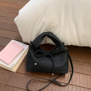 Close-up of black litchi texture PU leather bag with minimalist bow and silver hardware