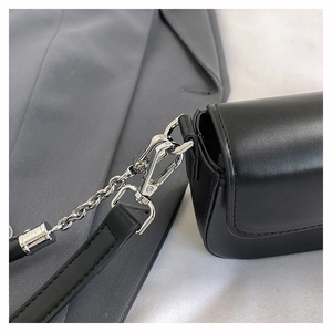 Detail of silver metal hook and fine stitching on a premium black leather shoulder bag