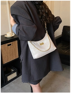 Detail of white half-moon bag with gold chain and texture worn as a crossbody bag