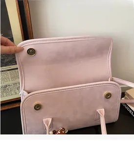 Detail of pink PU leather shoulder bag featuring magnetic gold buckles and fine stitching