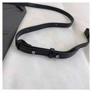 Detail of black leather shoulder strap with silver metal studs and adjustable holes