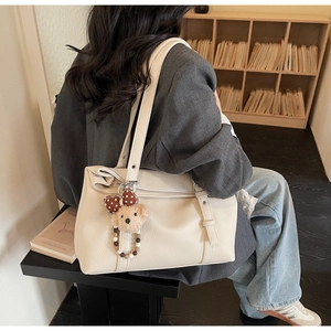 Détail d'un sac cabas en cuir grainé blanc cassé avec un charmant petit ours à pois bruns