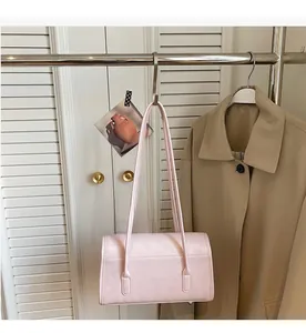 Detail of light pink shoulder bag with fine leather texture hanging on a metal hook