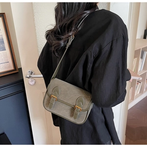 Sac baguette rétro gris-vert à doubles boucles présenté en porté épaule de style lifestyle