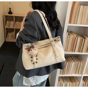 Détail du sac cabas crème avec cuir à texture litchi et pendentif ours mignon en peluche