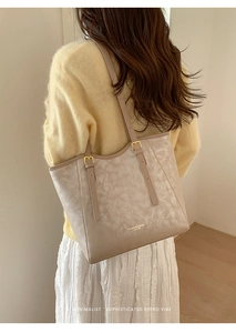 Detail of warm beige tote bag with marble texture and golden hardware on shoulder