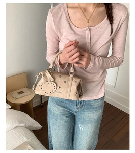 Beige pillow bag with star studs and heart pendant shown in a lifestyle setting