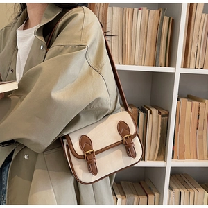 Détail d'un sac baguette rétro bicolore avec bordure en cuir marron et boucles en métal