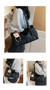 Vue détaillée du grand sac cabas en cuir noir avec un charmant pendentif en peluche