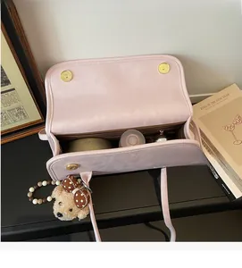 Pink matte shoulder bag showing spacious brown interior and cute bear pendant charm
