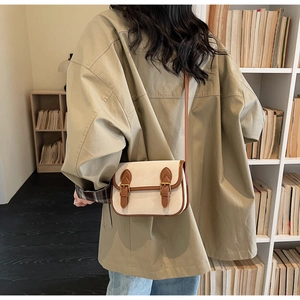 Détail du sac beige vintage avec lanières en cuir marron et boucles dorées