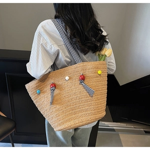 Detailed texture of a large straw tote bag with colorful beads and striped bow ribbon