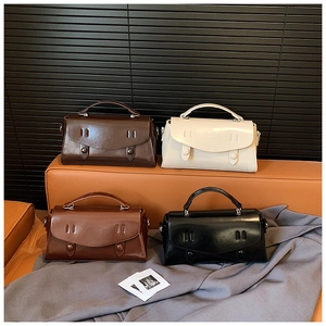 Detailed display of vintage satchel handbags in four colors on a leather bench