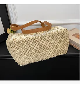 Close-up of beige woven straw tote bag with intricate crochet patterns and brown leather handles