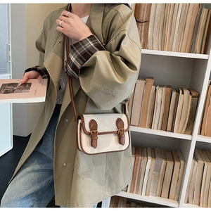 Détail d'un sac en toile avec garniture en cuir marron et boucles sur une étagère