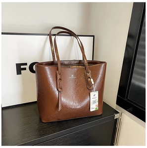 Detailansicht der braunen Leder-Tragetasche mit Logo und Retro-Faltenstruktur