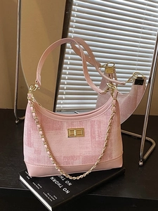 Pink woven leather underarm bag with gold chain and metal lock on a book background