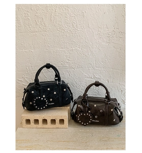 Detail of Boston bags with silver star studs and heart charm in black and brown leather