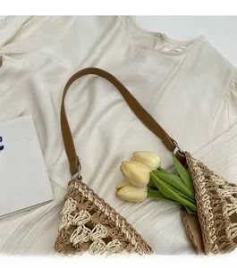 Détail du sac cabas en paille tissé à la main avec anses en cuir marron et fleurs