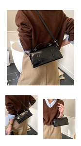 Close-up of glossy black patent leather flap bag with decorative circular buttons