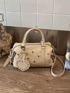 Retro beige Boston handbag with star rivets and heart charm on a wooden surface
