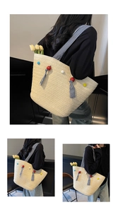 Détail du sac cabas en paille tissée avec pompons colorés et bandoulières rayées