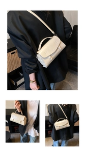 Macro view of cream baguette bag detail with double circular buckles and leather texture