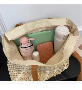 Spacious interior of woven straw tote bag holding sun umbrella, tablet and wallet