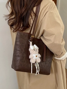 Retro dark brown large tote bag with cute pink bear charm on a khaki trench coat