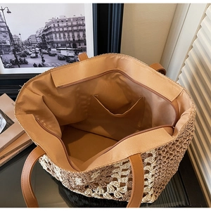 Detail of spacious straw tote interior featuring brown lining and zip pocket